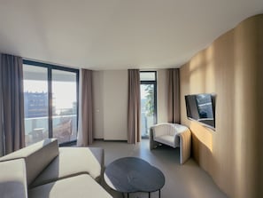 Una habitación de hotel moderna con sofá, sillón y una pequeña mesa redonda.