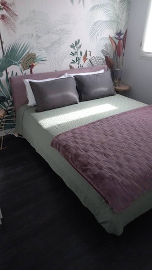 A bed with a green and purple bedspread, a headboard with a floral pattern, and a nightstand with a lamp. - Boutique Apartment "alla Dolce Vita" (Vicenza)
