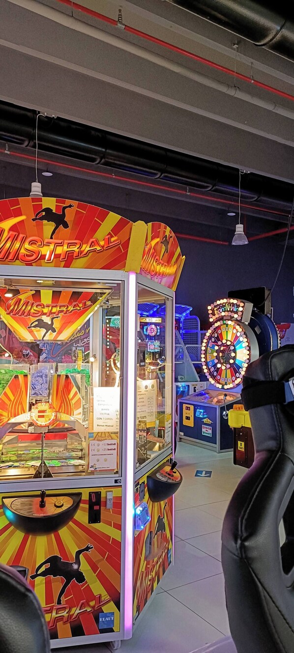 A brightly lit arcade game area with a 'Mistral' game machine and a 'BonWin' spinning wheel game. - Boutique Apartment "alla Dolce Vita" (Vicenza)