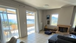 A spacious living area with a fireplace, a sofa, and a dining table. - Delos House Sounio Sea View Temple of Poseidon (Lavreotiki)