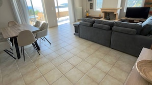 A spacious living area with a dining table, sofa, and a TV. - Delos House Sounio Sea View Temple of Poseidon (Lavreotiki)