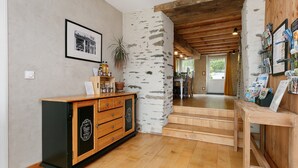 Un meuble en bois avec des tiroirs, un mur en pierre, un escalier et une table en bois sur laquelle sont posées des cartes postales.
