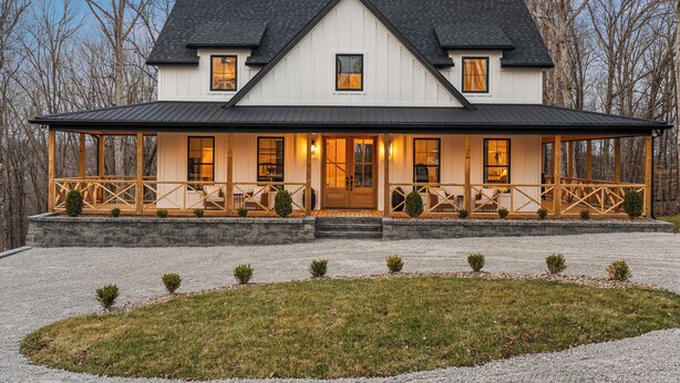 A two-story house with a covered porch, stone foundation, and a gravel driveway.