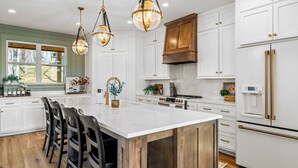 A modern kitchen with white cabinetry, a large island, and pendant lighting.