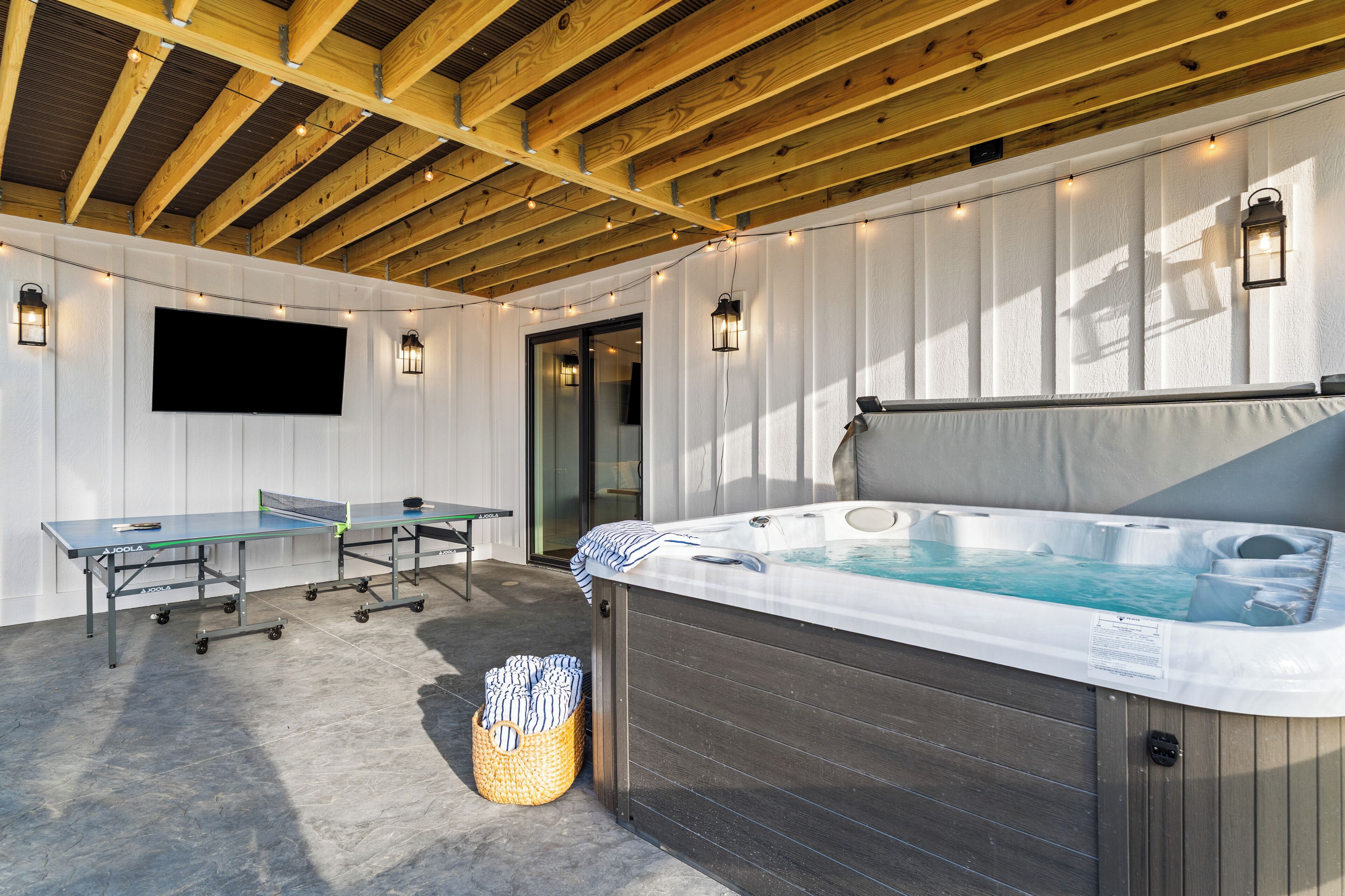 Un espacio al aire libre techado con mesa de ping pong, jacuzzi y zona de estar.