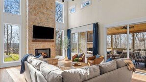 A spacious living room with a fireplace, large windows, and a view of the outdoors.