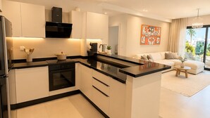 A modern kitchen with white cabinetry, a black countertop, and a built-in oven. - Appartement S+2 vue mer & golf - Premium hotel residence in Monastir (Monastir)