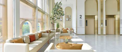 A spacious lobby with a long sofa, a coffee table, and a potted plant.