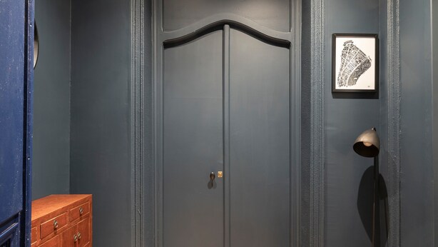 A room with a dark grey door, a wooden dresser, a framed map on the wall, and a floor lamp. - Charming Room in the Heart of Chartrons (Bordeaux)