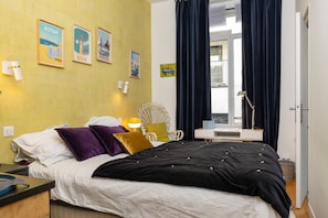 Ein Hotelzimmer mit Bett, Schreibtisch, Stuhl, Lampe und einem fenster mit Vorhängen.