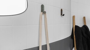 A bathroom with white tiled walls, a round mirror, and two wooden-handled towels hanging on hooks. - Charming Room in the Heart of Chartrons (Bordeaux)