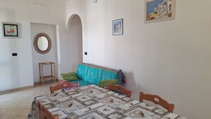 A dining area with a table set for four, a sofa, and a mirror on the wall. - La Serricella Mare vacation home, bright and comfortable just a stone's throw from the sea (Santa Cesarea Terme)