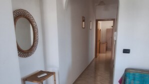 A hallway with a wooden bench, a mirror, and a colorful sofa. - La Serricella Mare vacation home, bright and comfortable just a stone's throw from the sea (Santa Cesarea Terme)