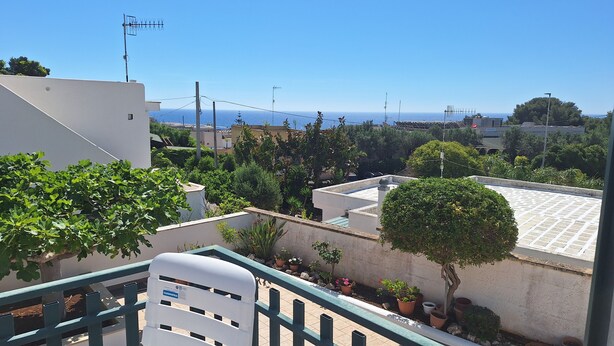 A residential area with a view of the sea, potted plants, and a white building with a balcony. - La Serricella Mare vacation home, bright and comfortable just a stone's throw from the sea (Santa Cesarea Terme)