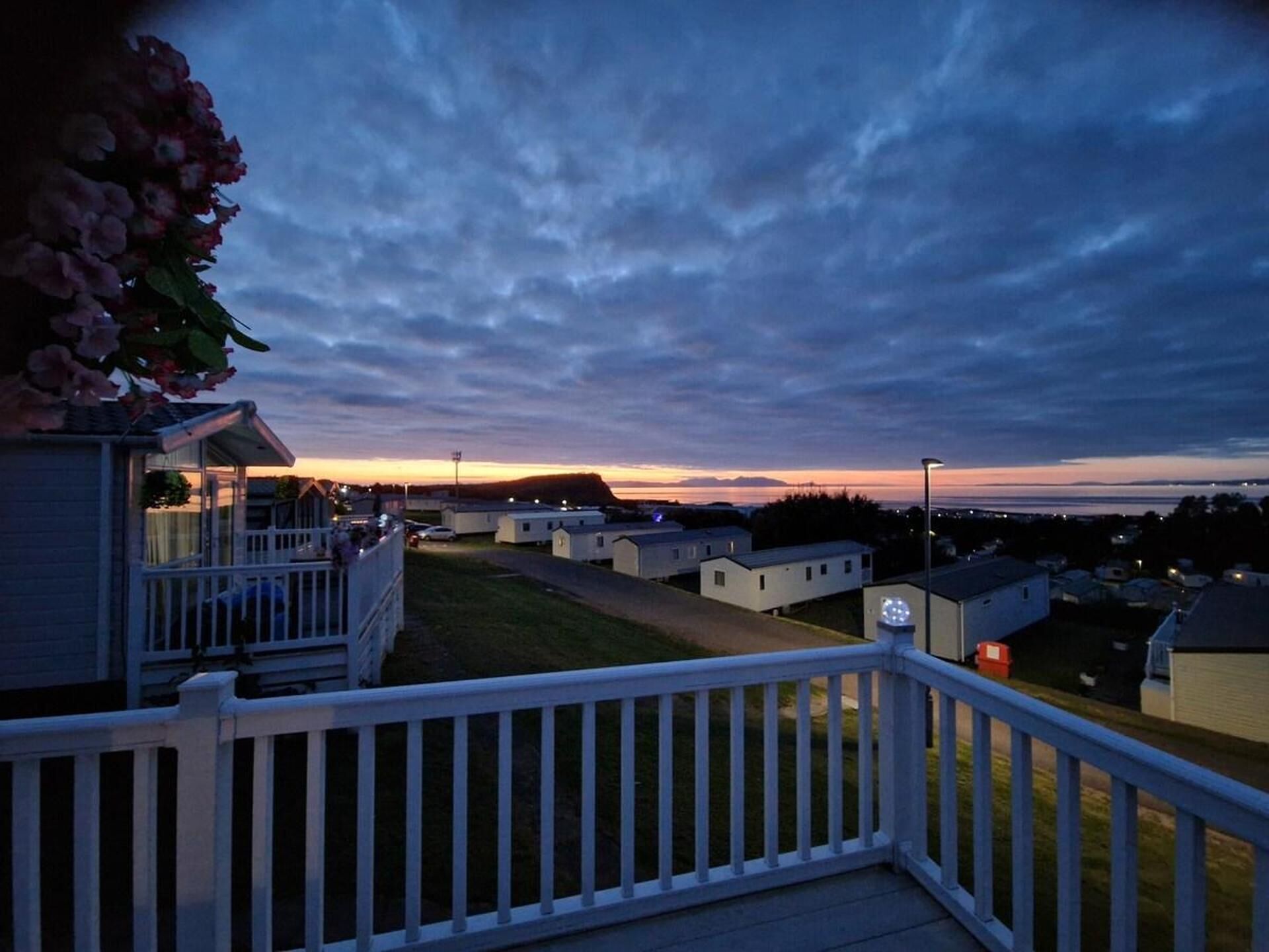 A residential area with houses, a white fence, and a clear sky.
