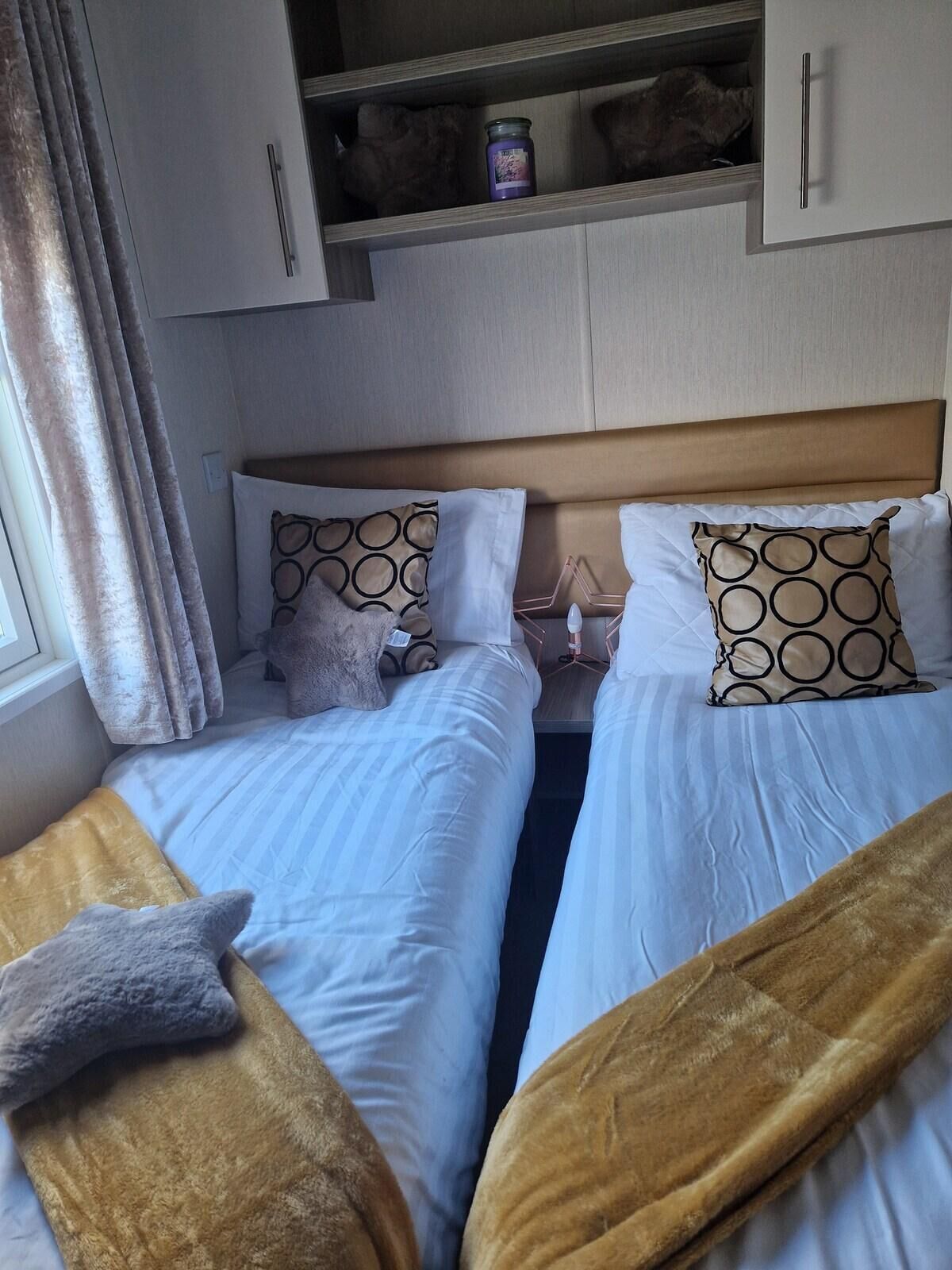 Une chambre avec deux lits, une armoire et une table de chevet avec une lampe.