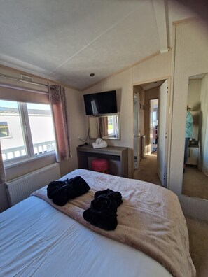 A hotel room with a bed, a desk, a TV, and a window. - Caravan Sleeps 6 - Sea Views, Parking, Pets (Ayr)