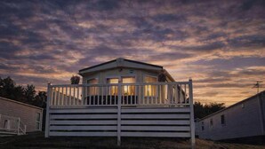 A single-story mobile home with a fenced porch, surrounded by trees.