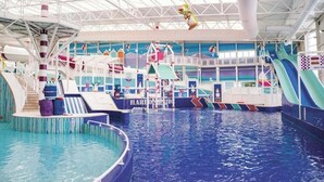 An indoor water park with a pool, slides, and a play area.