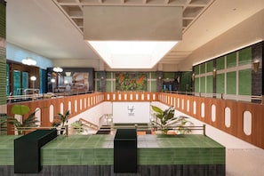 Un vaste atrium doté d’un escalier central, d’un espace d’accueil et d’un mur décoratif agrémenté de plantes.