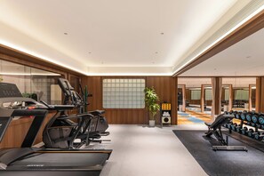 Une salle de sport moderne équipée de tapis de course, d’un vélo d’appartement et d’un banc de musculation.