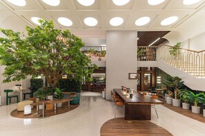 Un vaste espace intérieur doté d ’une grande table en bois au centre, de sièges et d’un grand arbre.