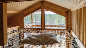 Eine Holzhütte mit einer Hängematte, großen Fenstern und Blick auf einen Wald.
