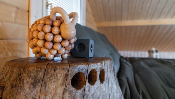 Une sculpture en bois, posée sur le tronc d’un arbre, avec un haut-parleur et une fenêtre en arrière-plan.
