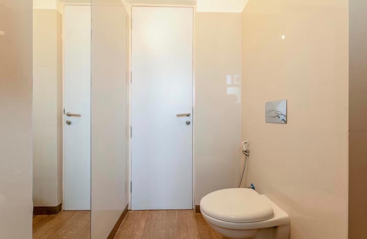 Een kleine, schone badkamer met toilet, douche en deur.