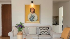 Un salon avec un canapé, un vase de fleurs et un tableau accroché au mur.