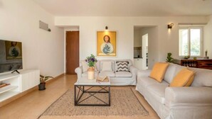 Un salon avec un canapé, une table basse et un tableau accroché au mur.