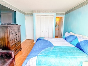 Ein Schlafzimmer mit Bett, Kommode und einer Tür zu einem Badezimmer.