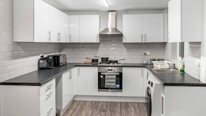 A modern kitchen with white cabinets, a stainless steel range hood, a built-in oven, and a dishwasher. - Stylsih 3BR House - Sleeps 5 - Near City Centre - Free Parking (Leeds)