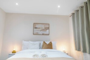 A hotel room with a neatly made bed, a bedside table with a lamp, and a painting on the wall. - Stylsih 3BR House - Sleeps 5 - Near City Centre - Free Parking (Leeds)
