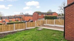 A residential area with brick houses, a wooden fence, and a grassy yard. - Stylsih 3BR House - Sleeps 5 - Near City Centre - Free Parking (Leeds)