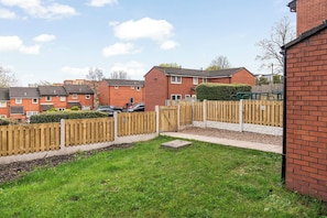 A residential area with brick houses, a wooden fence, and a grassy yard.