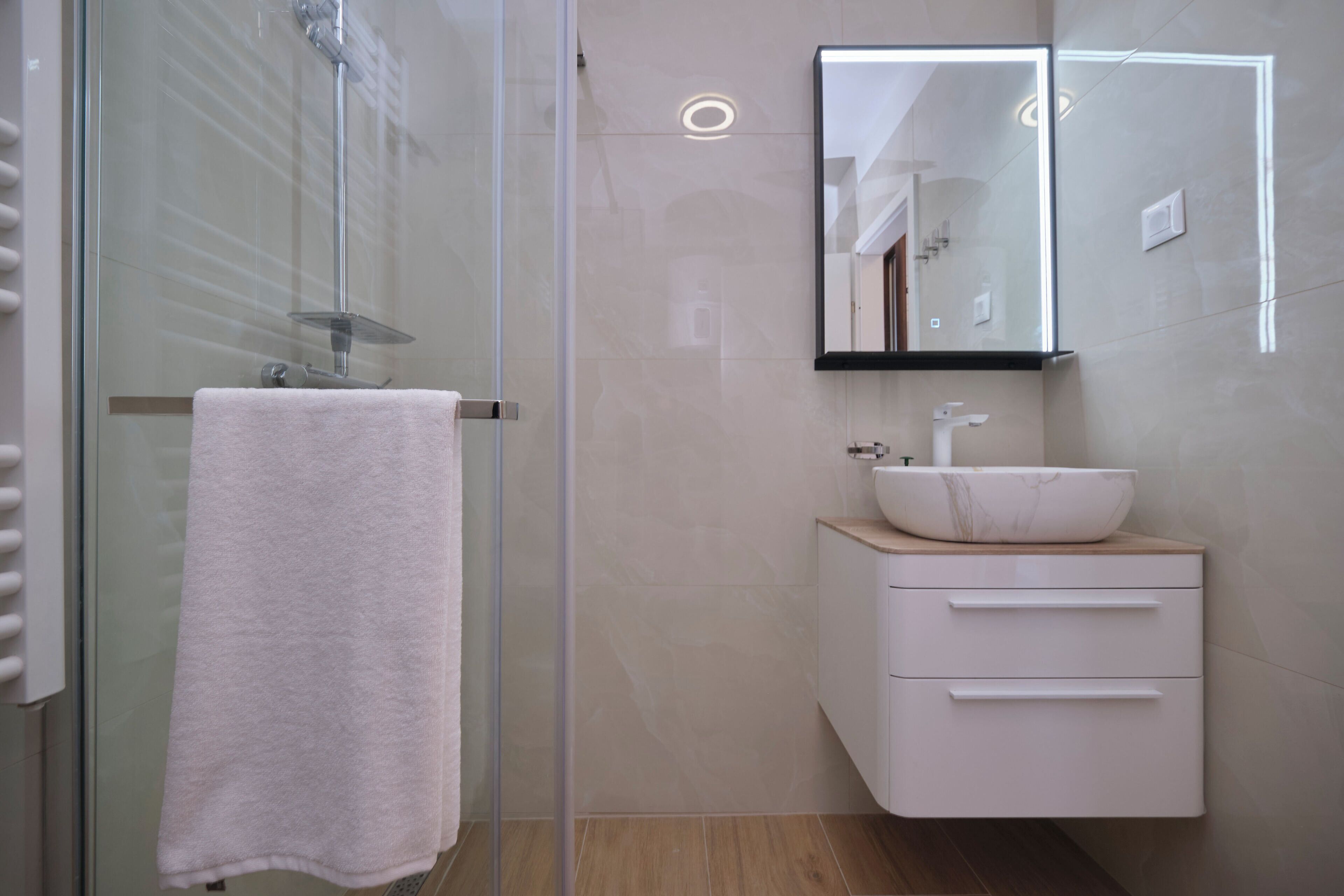 Une salle de bain moderne avec une douche à parois de verre, un lavabo blanc et un miroir au-dessus.