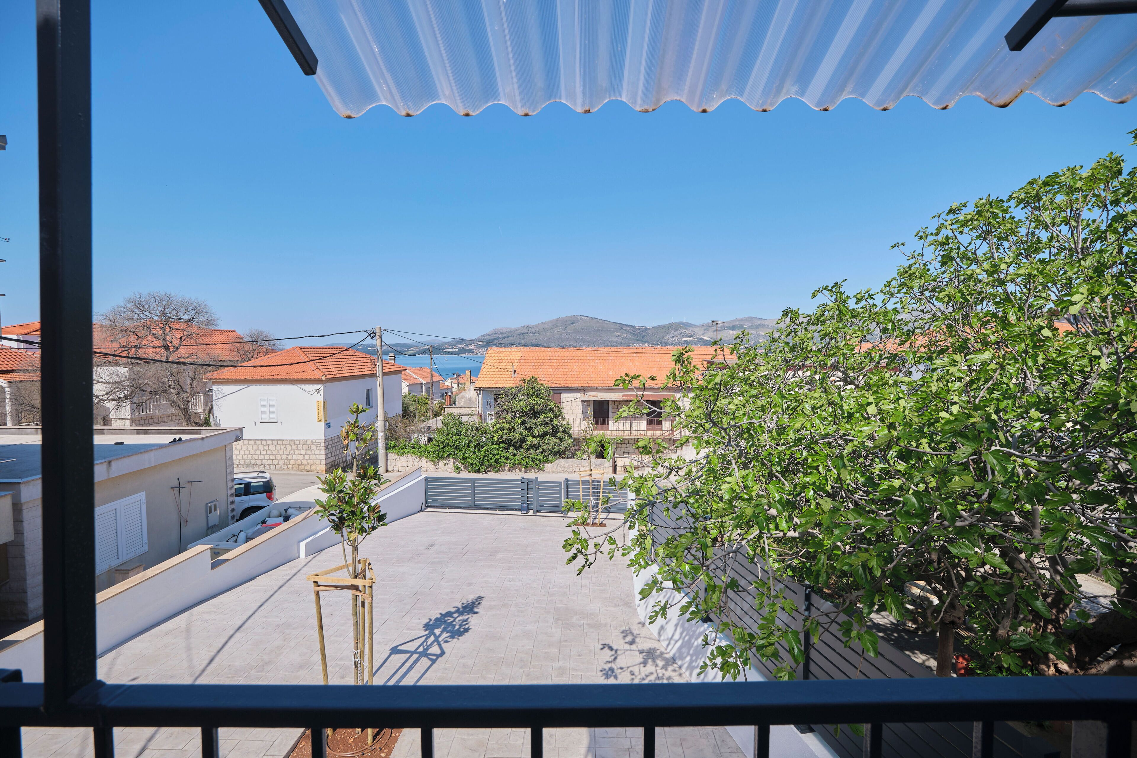 En balkon med udsigt over et boligområde, en klar himmel og fjerne bjerge.