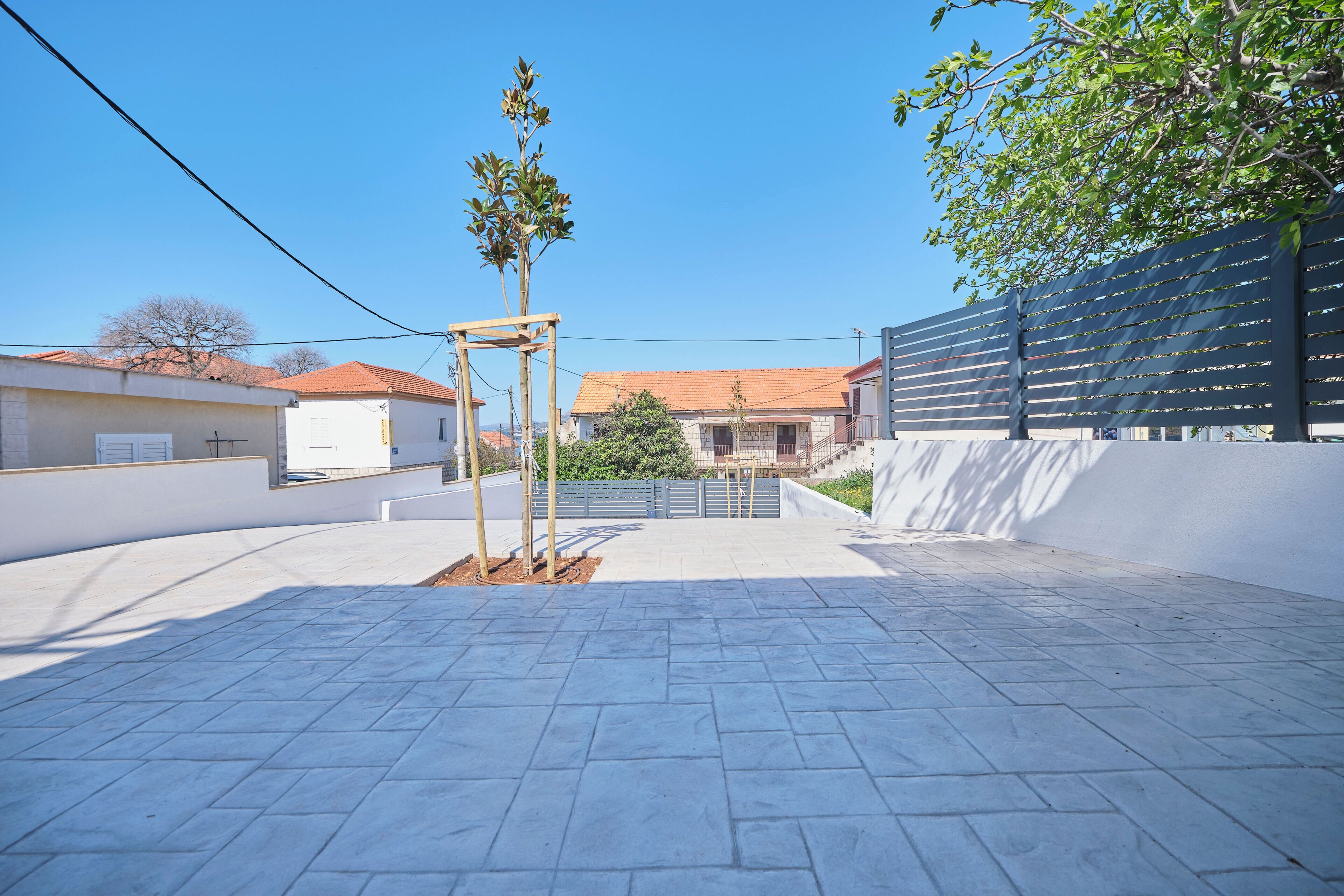 Une cour avec un sol pavé, une structure en bois et une clôture.