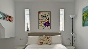 A bedroom with a bed, two bedside tables, a lamp, and artwork on the wall. - Apartamento Carús - Ole Solutions (Jerez de la Frontera)