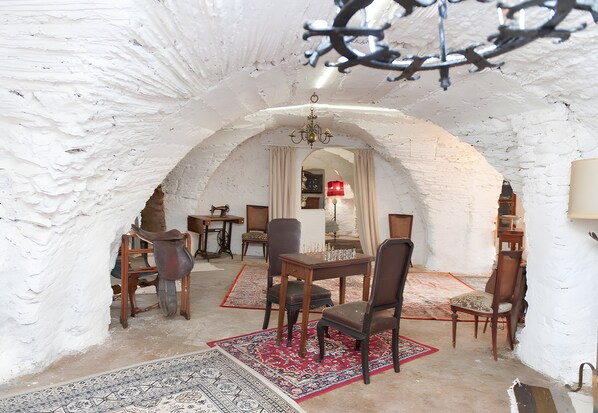 An arched room with a chandelier, a dining table, chairs, and a patterned rug.