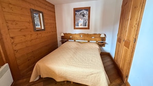 Ein Zimmer mit Holzwänden, einem Bett, einem gerahmten Bild an der Wand und einer Holztür.