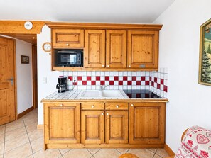 A kitchen with wooden cabinets, a microwave, a sink, and a tiled backsplash. - Comfortable apartment with clear view - 4 guests (Les Menuires)
