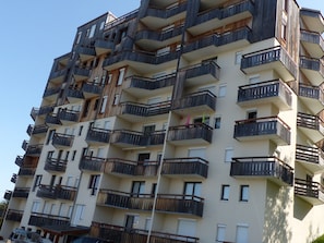 Ein mehrstöckiges Wohngebäude mit Balkonen und Fenstern vor blauem Himmel.