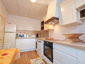 Una cucina compatta con frigorifero, microonde, tostapane e forno.