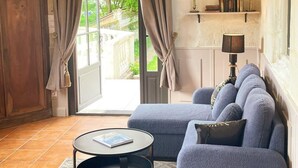 A living room with a sofa, a round table, and a bookshelf. - Charming chapel, pool near Loire (Bréhémont)