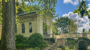 A historic building with arched windows, a stone staircase, and a bridge leading to an entrance. - Charming chapel, pool near Loire (Bréhémont)