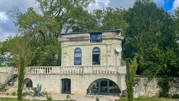 A two-story stone building with a balcony, arched windows, and a satellite dish. - Charming chapel, pool near Loire (Bréhémont)