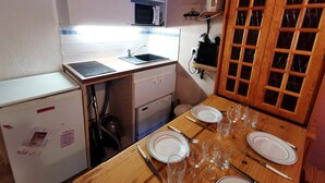 Une cuisine compacte équipée d’un évier, d’un four à micro-ondes et d’une table à manger pour quatre personnes.