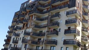 Un immeuble résidentiel à plusieurs étages, doté de balcons et de fenêtres, avec un ciel dégagé.